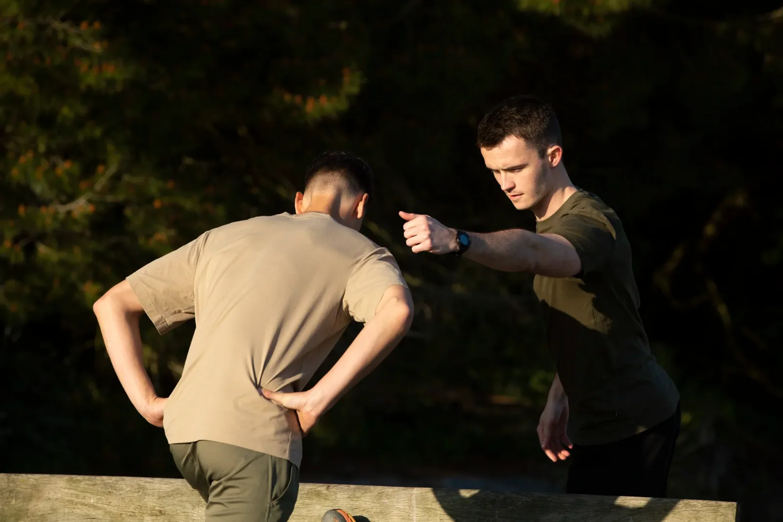 Coach sportif corrigeant la posture d'un client pendant une séance en extérieur